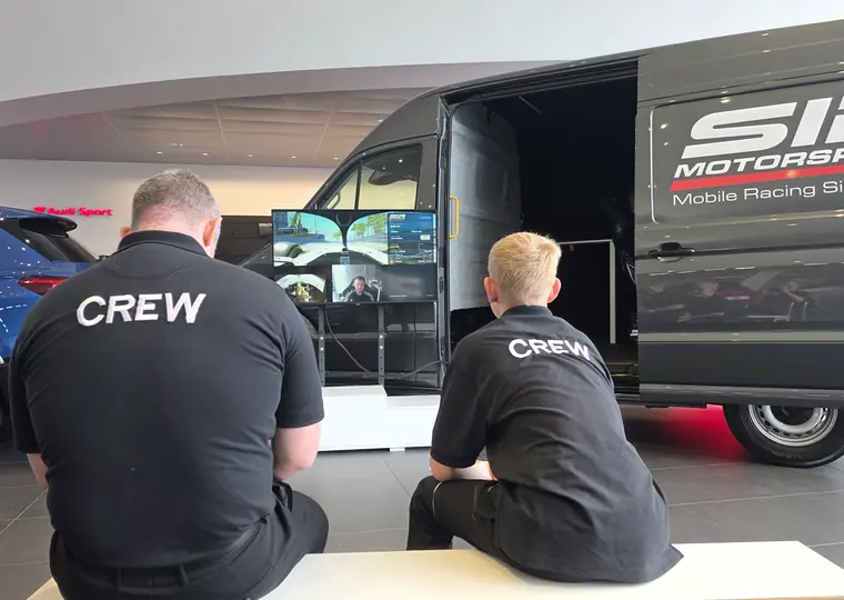 SIR Motorsport crew with the mobile racing simulator van at an indoor event venue.